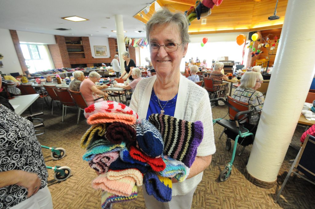 A photo of a elderly woman in Harmony Hall and festive items she knitted for Christmas.