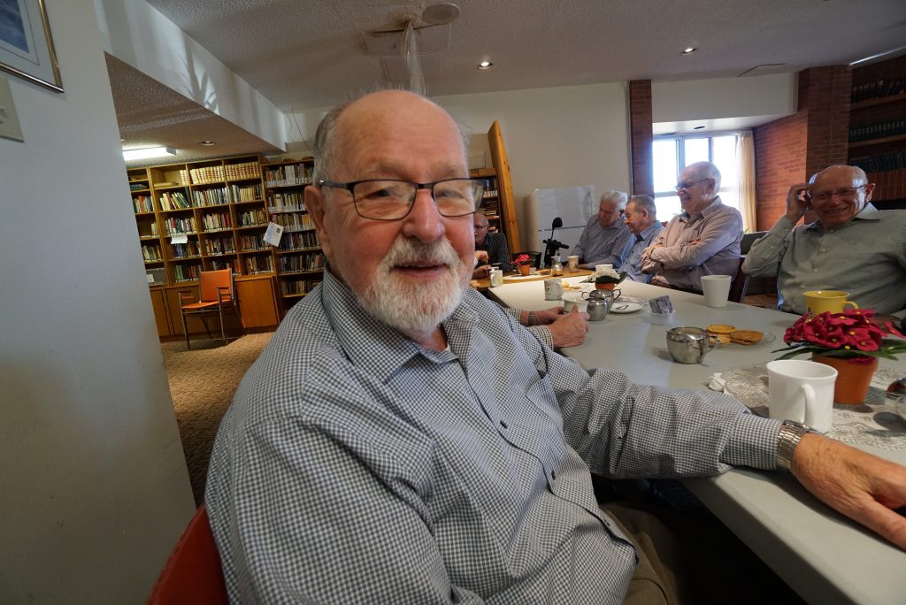 A photo of elderly men enjoying coffee and tea inside of Harmony Hall.