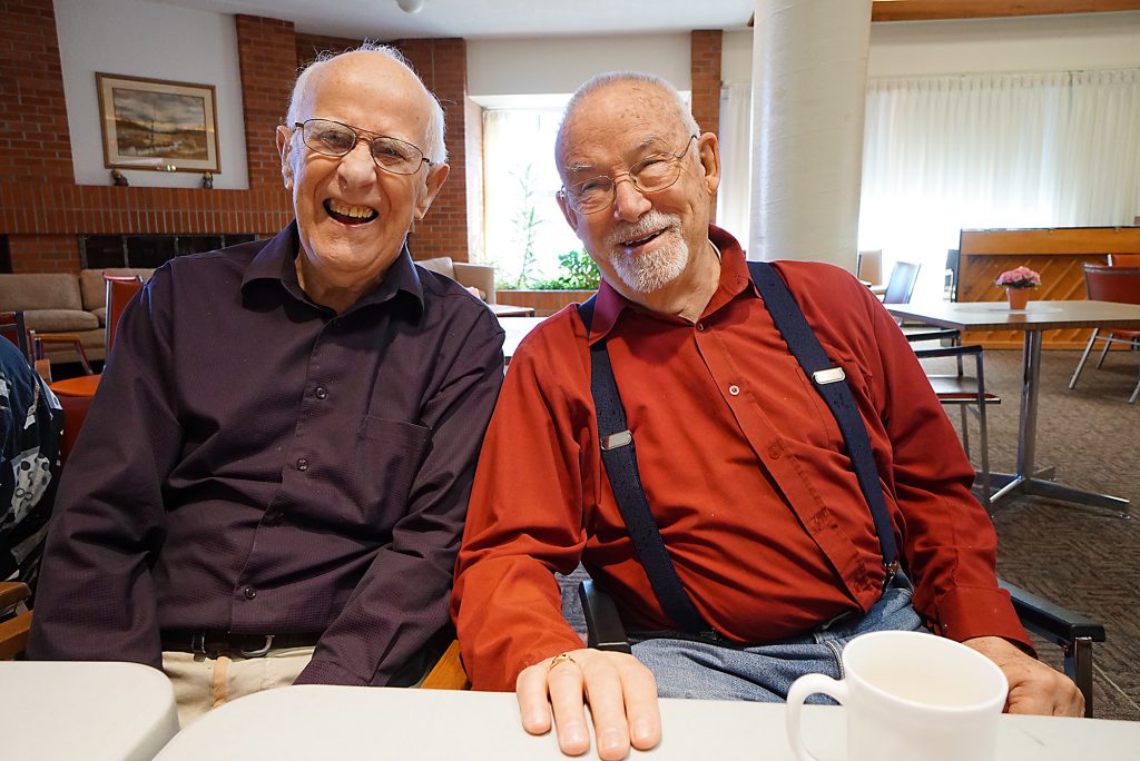 A photo of two elderly gentlemen having a friendly conversation in Harmony Hall.