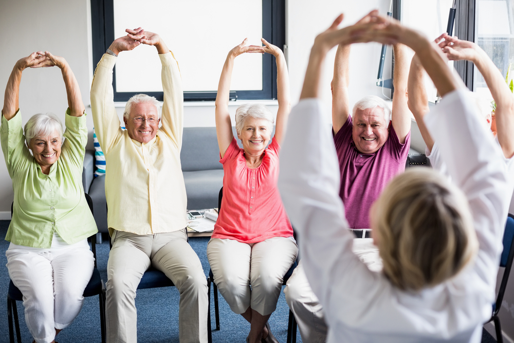 A photo of a elderly group participating in a Yoga program instructed by a Yogi.