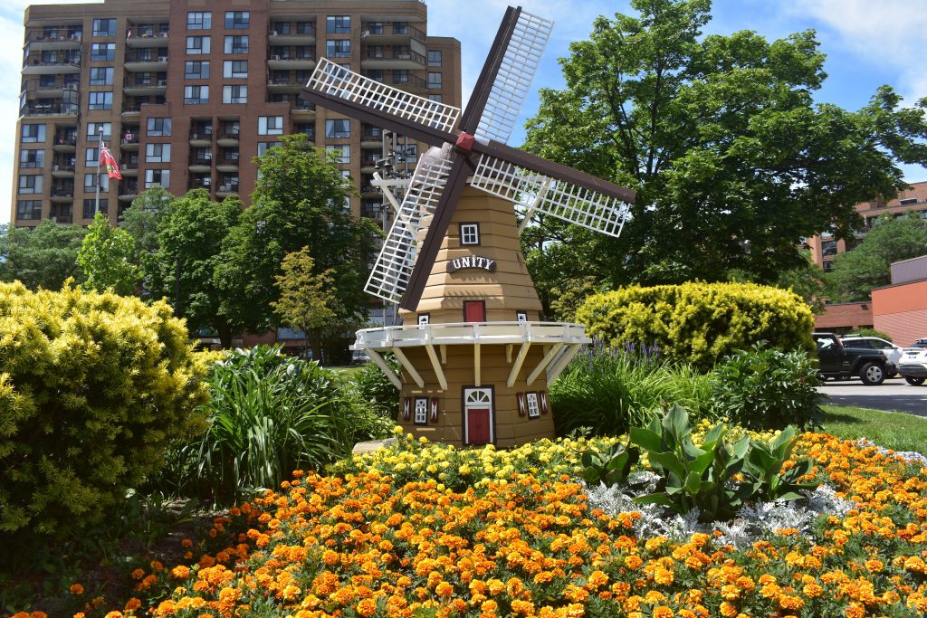A picture of the outside of the main entrance going into Covenant Tower and a Windmill lawn decoration that has the word "Unity" on it.