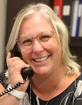 A picture of Kelly Pereira smiling while taking a phone call with a tenant.